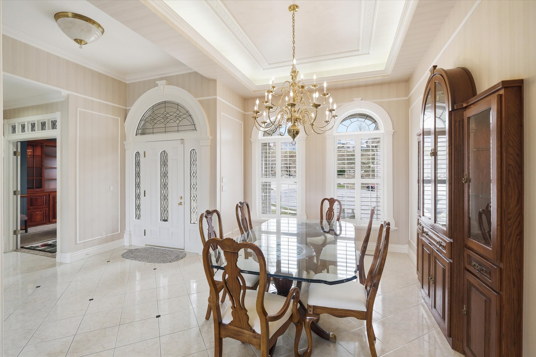 Dining area with hanging lights, light tile patterned flooring, ornamental molding, and a tray ceiling