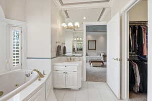 Full bathroom featuring wallpapered walls, a spacious closet, vanity, crown molding, and hanging lights