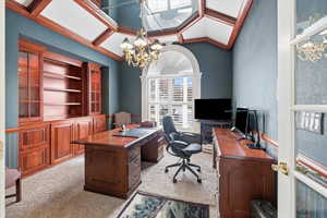 Office space with light colored carpet, coffered ceiling, a chandelier, and lofted ceiling
