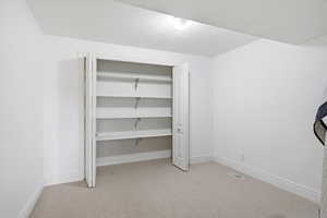 Unfurnished bedroom with light carpet, a closet, and a textured ceiling