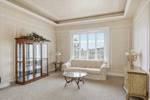 Living area with carpet floors and a tray ceiling