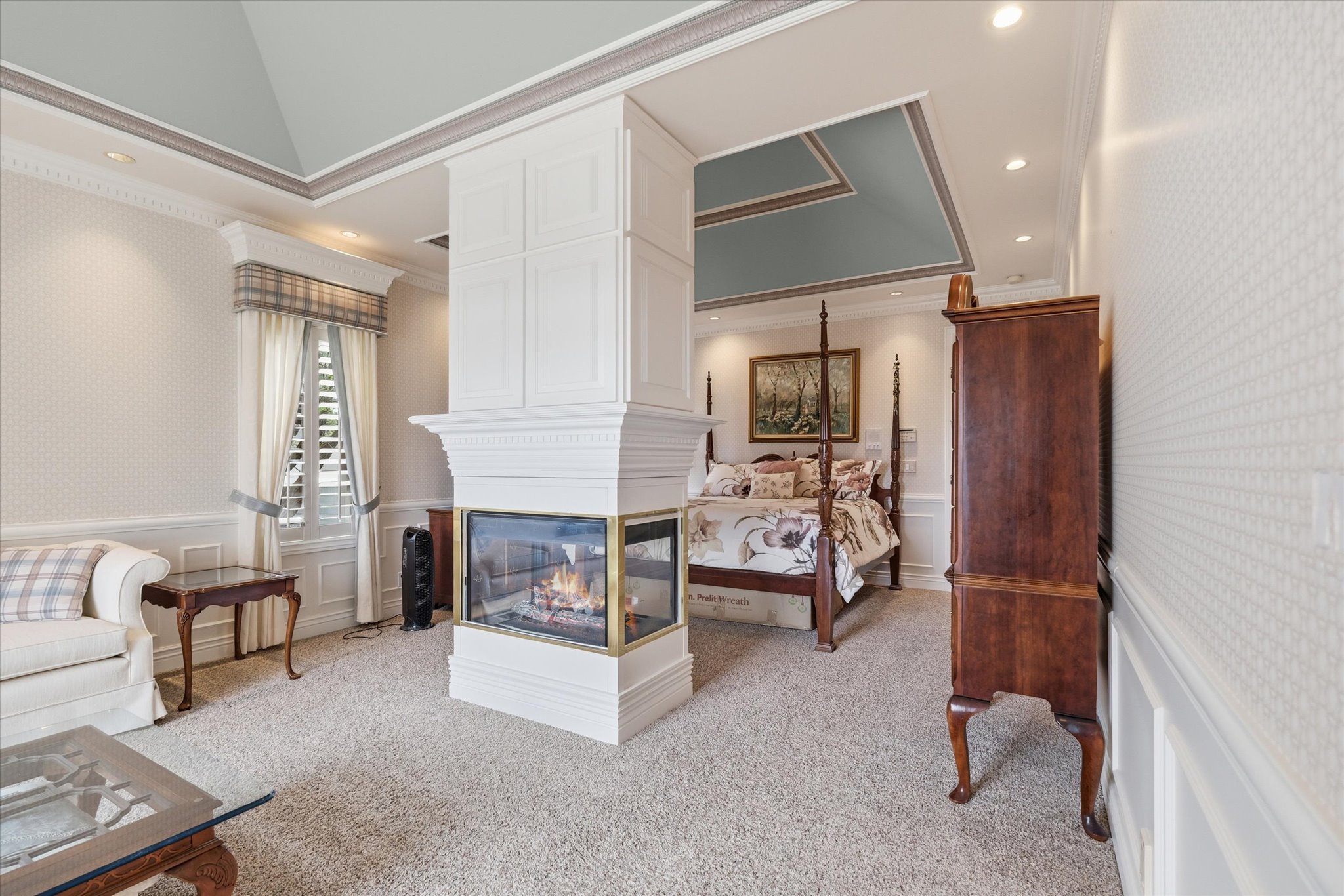 Bedroom with wainscoting, a decorative wall, wallpapered walls, light colored carpet, and ornamental molding
