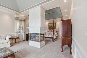 Bedroom with wainscoting, a decorative wall, wallpapered walls, light colored carpet, and ornamental molding