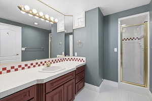 Bathroom with a stall shower, vanity, light tile patterned floors, a textured ceiling, and tasteful backsplash