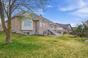 Back of property featuring brick siding, a patio, and a deck