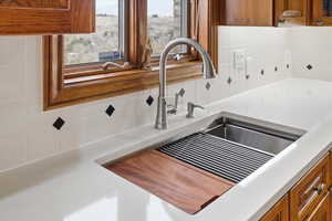 Kitchen view of wood finish cabinetry, decorative backsplash, and light stone counters