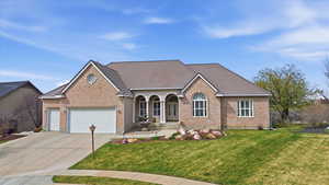 View of front of home with brick siding, a garage, a front lawn, and driveway