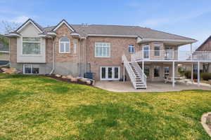 Rear view of property featuring a patio area, brick siding, a lawn, and french doors