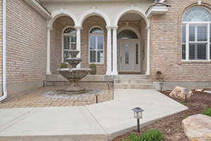 View of exterior entry featuring brick siding and a porch