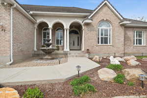 Doorway to property featuring brick siding and a porch