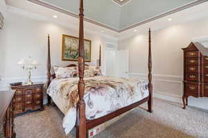 Carpeted bedroom featuring a wainscoted wall, a decorative wall, and crown molding