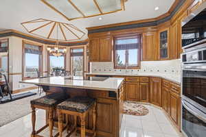 Kitchen with stainless steel appliances, a kitchen bar, wood finish cabinetry, tasteful backsplash, and a kitchen island