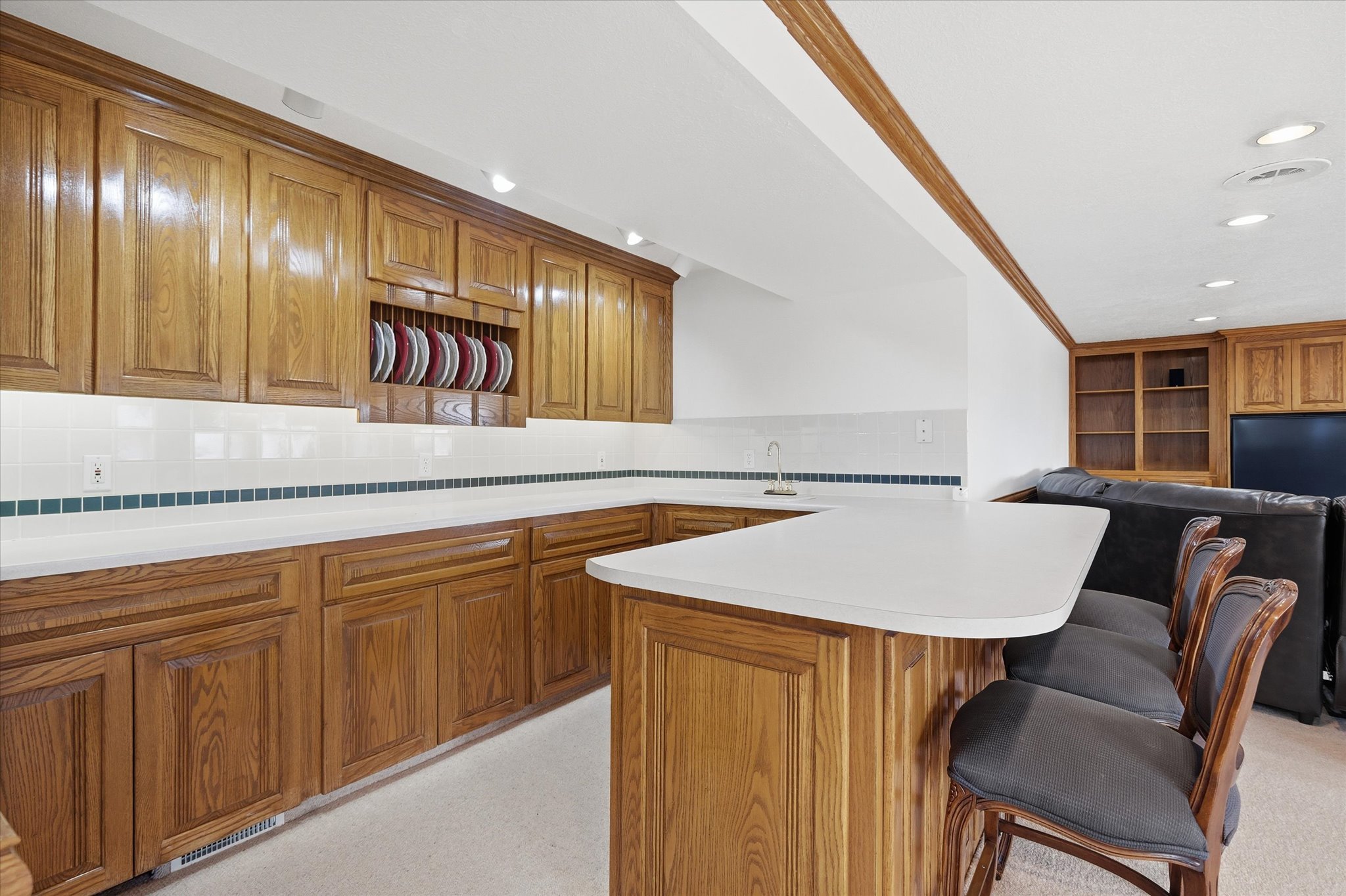 Kitchen with open floor plan, a breakfast bar, light countertops, tasteful backsplash, and wood finish cabinetry