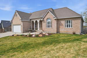 View of front of home with brick siding, a front lawn, concrete driveway, and a porch