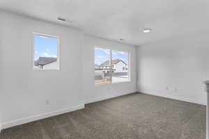 Spare room with baseboards and dark carpet