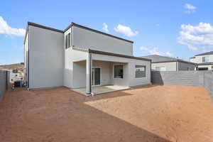 Rear view of house with a fenced backyard, stucco siding, and a patio