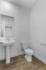 Half bath featuring toilet and dark wood-type flooring