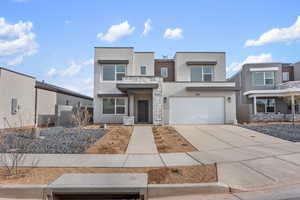 Contemporary house with stucco siding, driveway, stone siding, and an attached garage