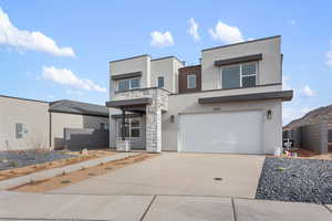 All photos are of a similar model.Modern home featuring stucco siding, driveway, a garage, and stone siding