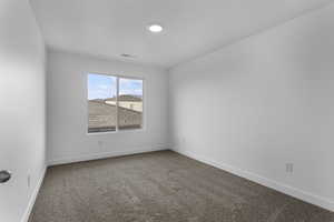 Empty room featuring dark carpet and baseboards