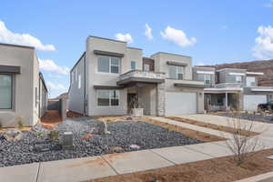 Contemporary house featuring concrete driveway, stucco siding, stone siding, and a garage