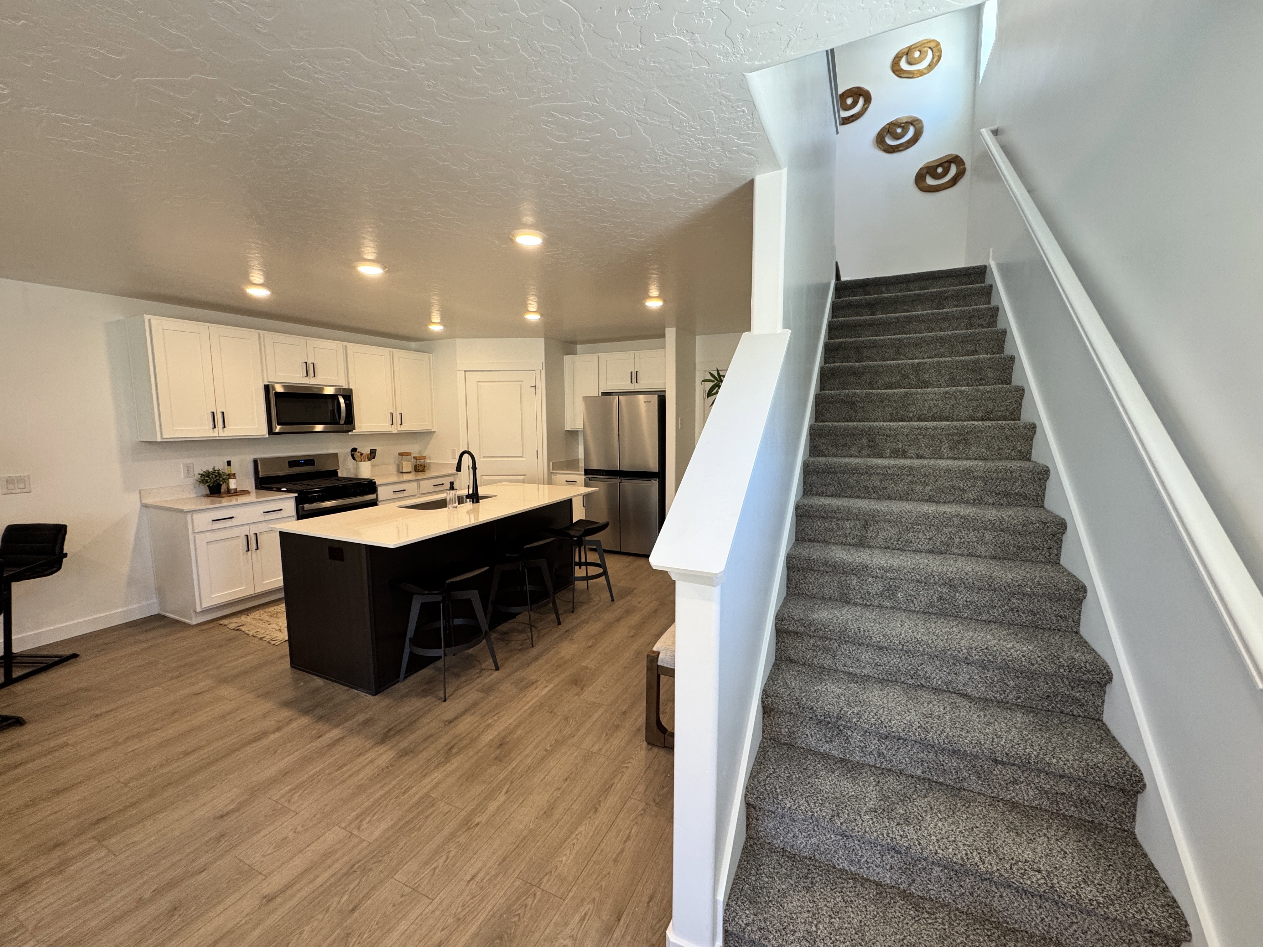 Modern kitchen featuring white cabinetry, stainless steel appliances, a center island with seating, and wood-finish flooring