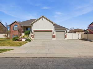 View of front of property featuring brick siding, an attached garage, concrete driveway, a gate, and a porch