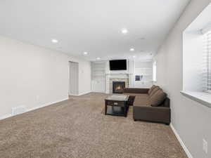 Carpeted living room featuring built in features, a fireplace, and recessed lighting