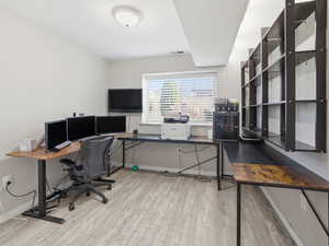 Office with light wood-type flooring and baseboards