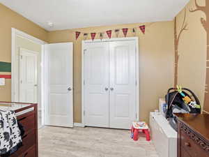 Bedroom with light wood finished floors, a closet, and white refrigerator