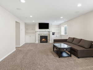Living room with built in shelves, light carpet, a fireplace, and recessed lighting