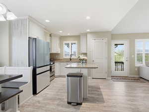 Kitchen with stainless steel appliances, a center island, light wood finished floors, and light stone counters