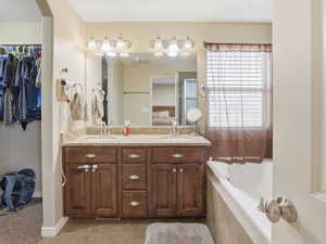 Bathroom featuring double vanity, a bath, light tile patterned flooring, a spacious closet, and connected bathroom