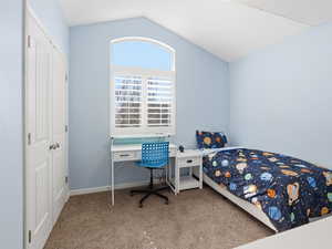 Bedroom with light carpet, lofted ceiling, and a closet
