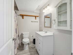 Full bathroom with vanity, a shower with shower curtain, and a textured ceiling