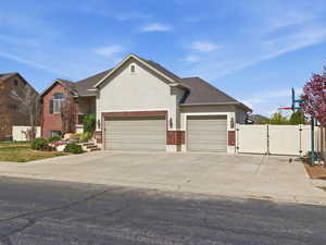 View of front of home with brick siding, a garage, concrete driveway, stucco siding, and a gate