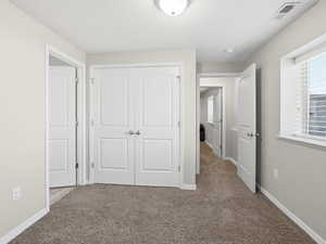 Unfurnished bedroom featuring a closet and light colored carpet