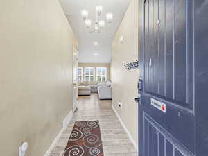 Doorway to outside featuring wood finished floors and a chandelier