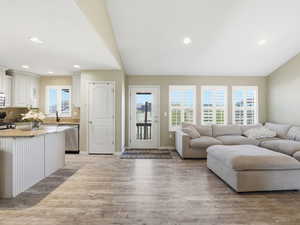 Living area with light wood finished floors and recessed lighting