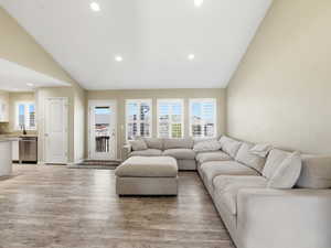 Living area with lofted ceiling, light wood finished floors, and recessed lighting