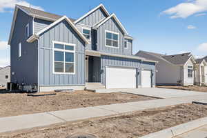 View of front of property with board and batten siding, concrete driveway, and an attached garage
