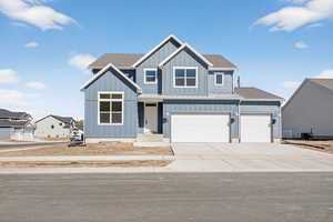 View of front of home with board and batten siding, concrete driveway, roof with shingles, and a garage