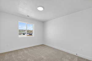 Spare room with light carpet and a textured ceiling