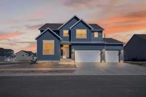 View of front of house with board and batten siding, a standing seam roof, driveway, an attached garage, and a garage