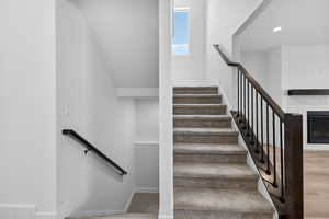 Stairway with a glass covered fireplace and carpet