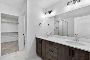 Bathroom featuring double vanity, a spacious closet, a stall shower, light carpet, and light tile patterned flooring