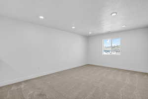 Unfurnished room with light carpet, recessed lighting, and a textured ceiling