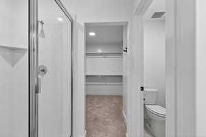 Full bath with a walk in closet, a shower stall, light carpet, and recessed lighting