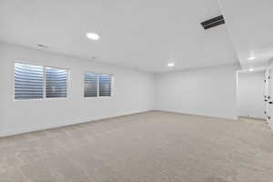Below grade area with light carpet and recessed lighting