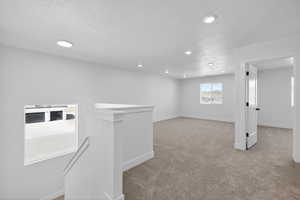 Below grade area featuring light carpet, recessed lighting, and a textured ceiling